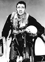 John Boyd as a young fighter pilot in flight harness, holding his helmet beside the jet's cockpit